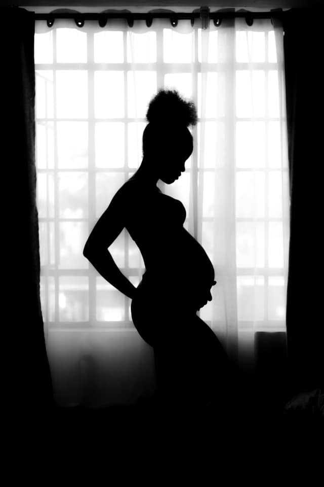 Photo of the shadow of a pregnant woman in front of a bright window
